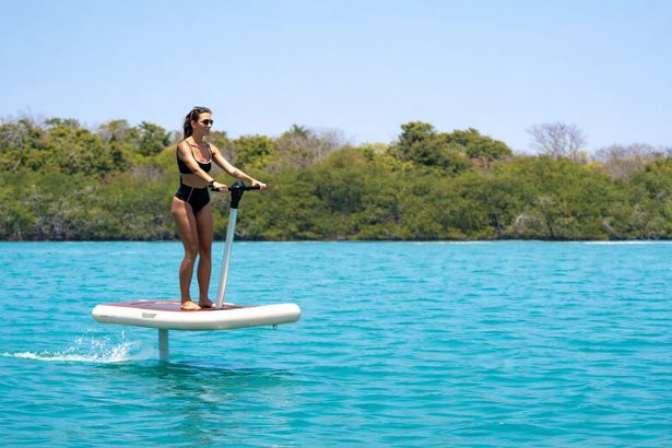 Mujer practicando E-Foil sobre el agua turquesa