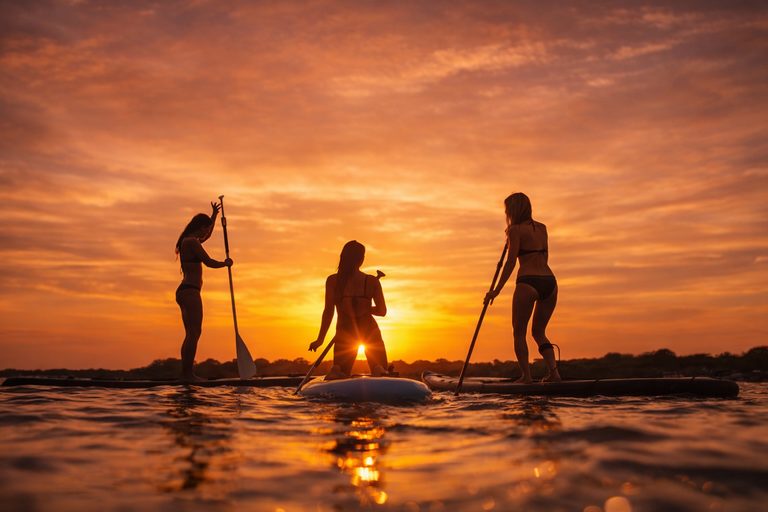 Tres personas haciendo paddle board al atardecer