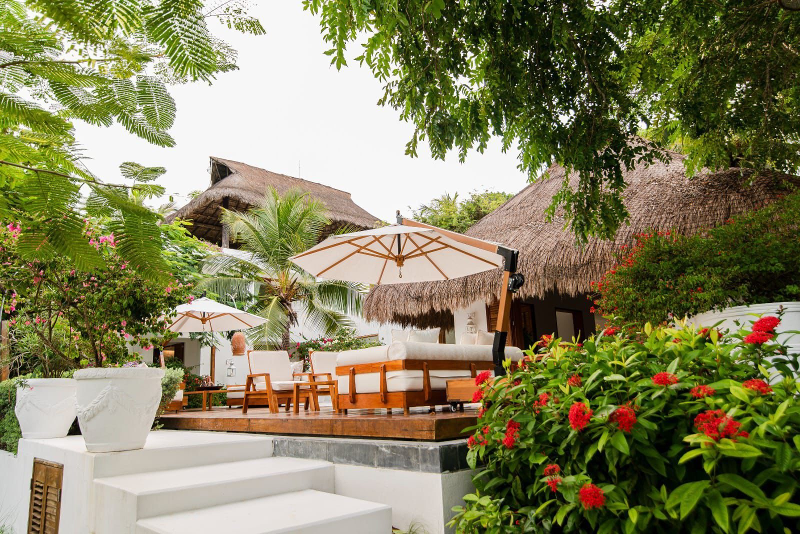 Exterior de la villa con techos de palma y jardines
